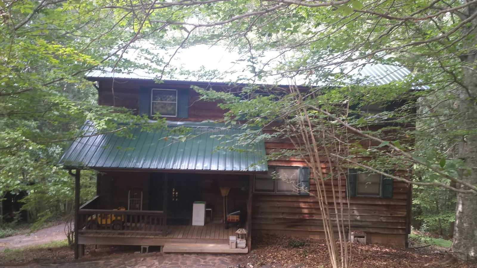 Green metal roof and covered porch on a log cabin in Valley City