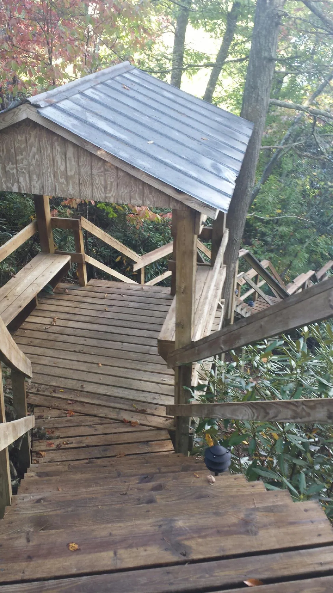 Metal roofed shelter over wooden steps on a wooded walkway — Skylight Repair & Installation work by our crew in Valley City