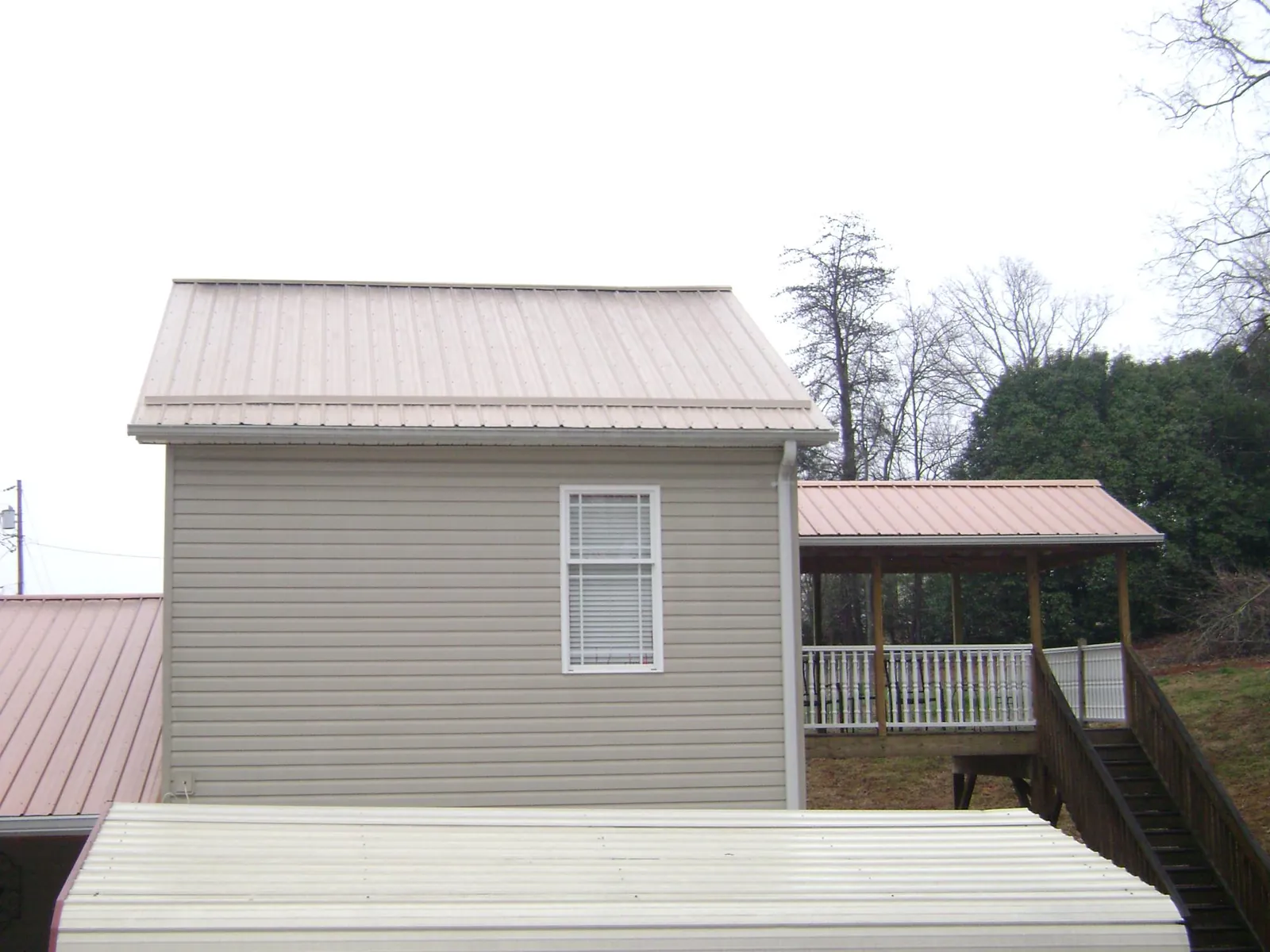 Tan metal roofs on a two story addition and attached porch, from a Roof Replacement job in Valley City