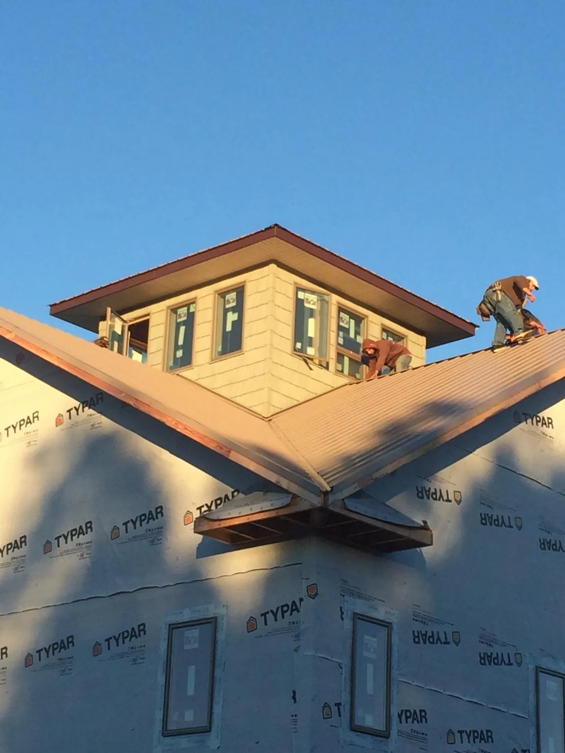 Roofers working around a rooftop cupola on a new metal roof at sunset — Roof Waterproofing in Valley City by Roofing Brothers